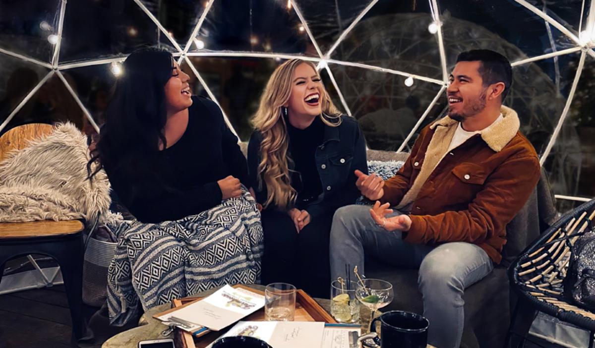 Friends enjoy laughter and drinks inside a Fair Oaks Farms heated igloos.