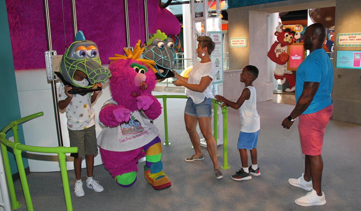 A family playing with mascot heads at the Mascot Hall of Fame