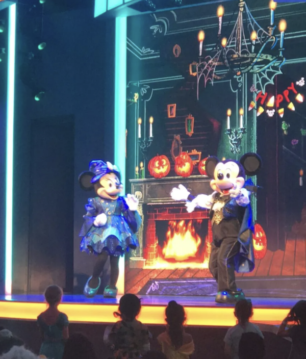 Mickey and Minnie Mouse dressed up in their Halloween costumes and dancing on stage.