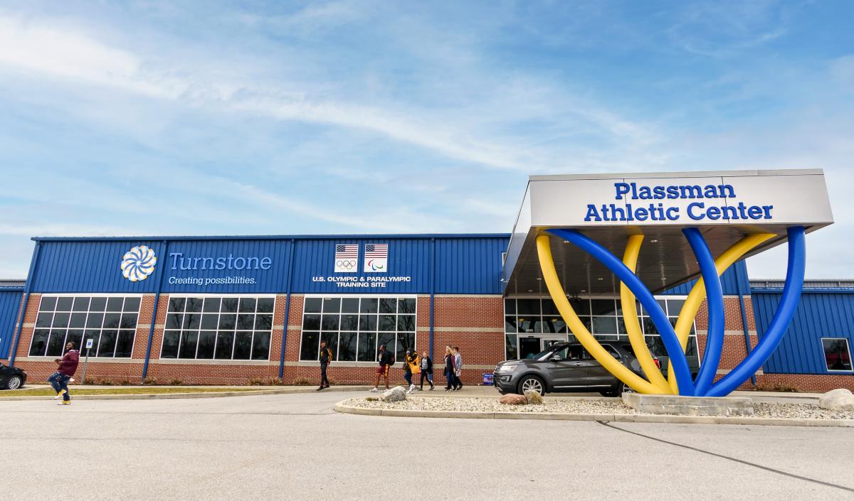 Exterior of the Plassman Athletic Center at Turnstone shows a colorful blue and yellow portico and the Olympic training designation signage