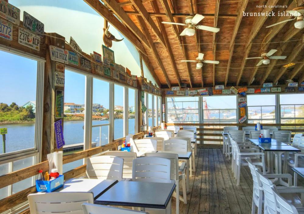 dining room with large windows and walls covered in license plates filled with white tables and chairs
