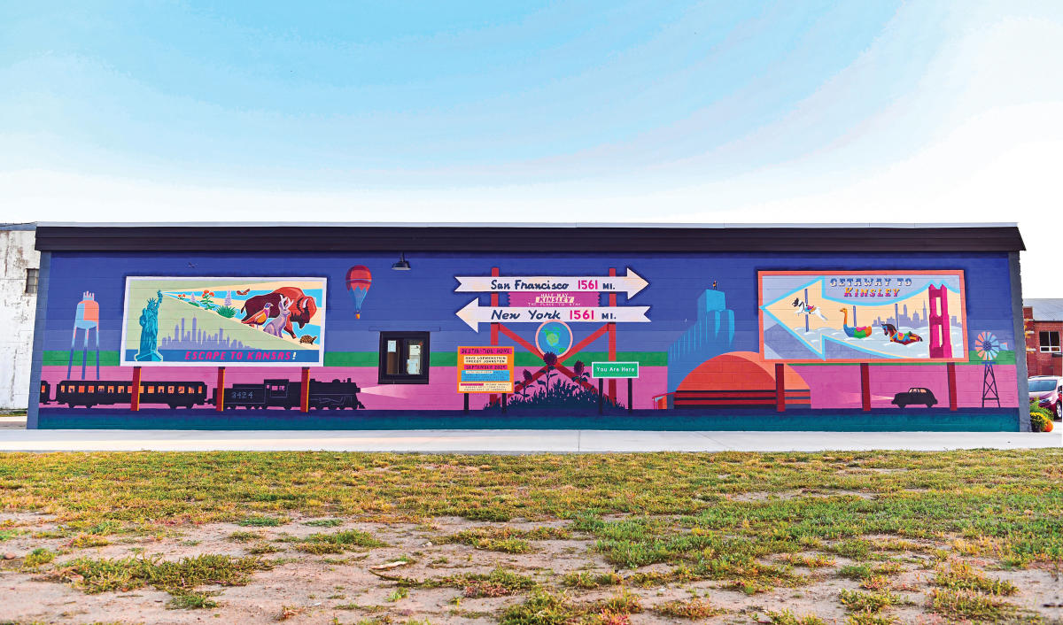 a wide angle of wall mural on the side of a building, it's vibrant colors of pinks, blues and purples.