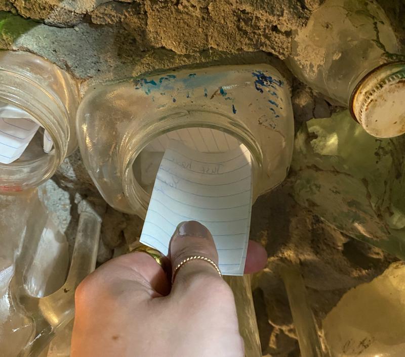 Someone places a note in a bottle in the wall at Tinkertown Museum