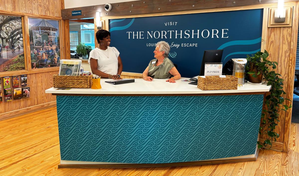 Zondra White Jones and Annette Shurtz welcoming visitors at the front desk inside the Visit The Northshore Visitor Center in Mandeville, Louisiana