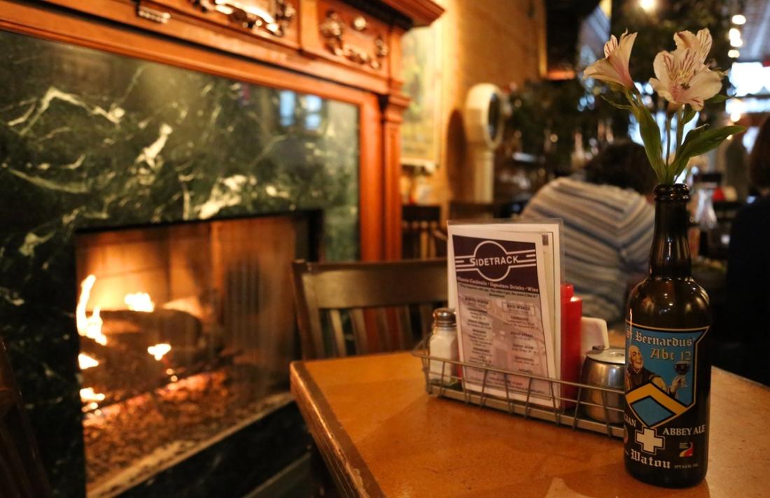 An empty table sits at a restaurant in front of an active fireplace.