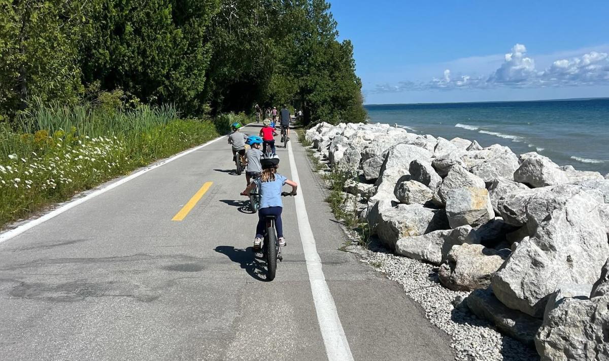 Bicycle riders of all ages pedal along the waterfront on Mackinac Island