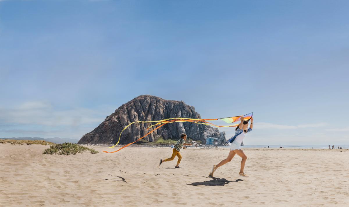 kids playing with kites on beach in front of Morro Rock