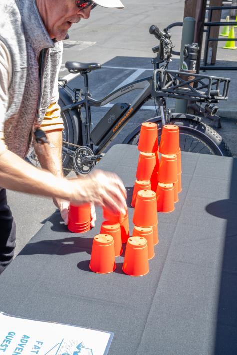 A man attempts to stack and unstack cups in a vertical fashion to complete a task during a game.