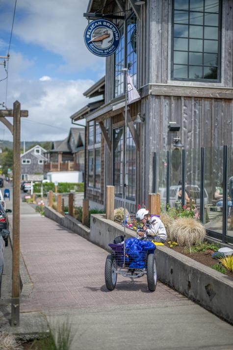 A person sitting on the sidewalk near Pelican Brewing Company during the Fat Bike Festival in Cannon Beach