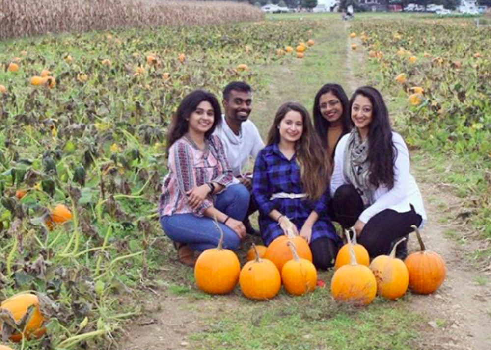 A group of people posing with pumpkins in a field at Lee Turkey Farm