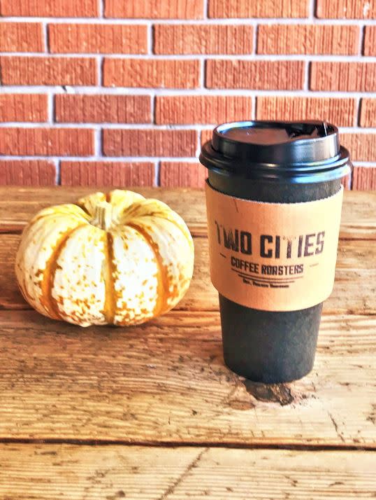 Small pumpkin next two black coffee cup