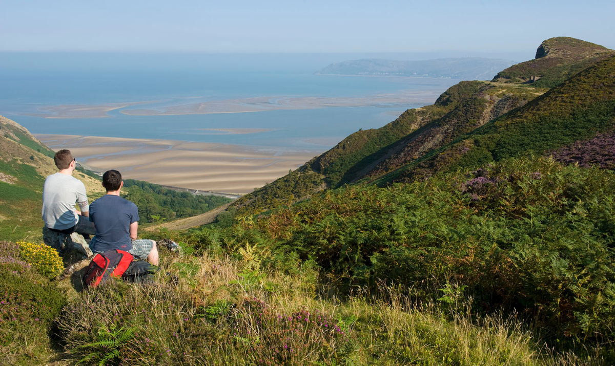 Two people sitting and looking out over the sea from high up in the mountains