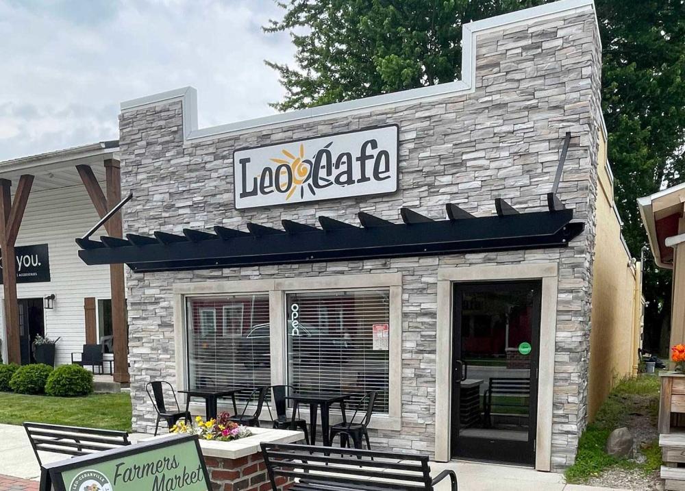 The exterior of Leo Cafe with a black awning and beige stone.
