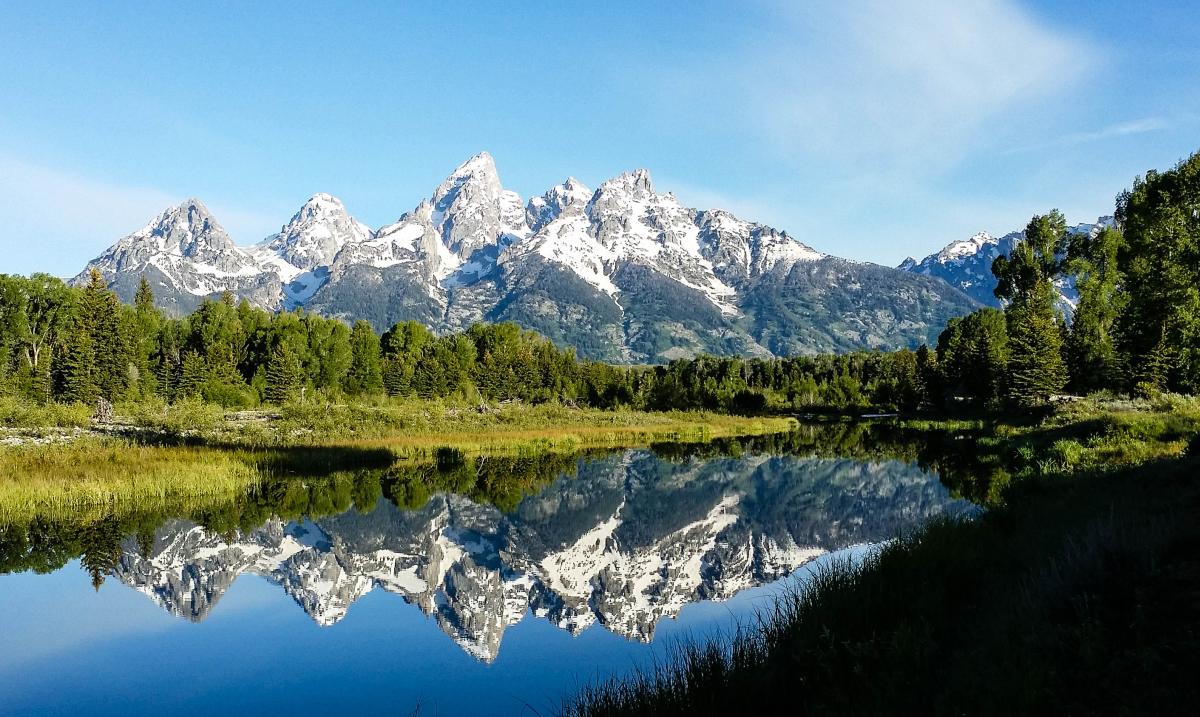The Grand Tetons reflect against the lake from Schwabaucher Landing