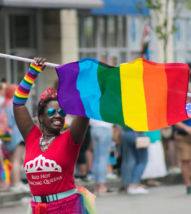 Young Black woman in the dance group Red Hot Dancing Queens holding a Pride flag