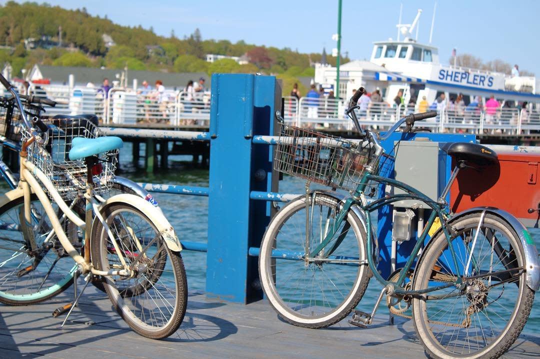 Dock porter bicycles rest against a blue railing in front of a Shepler’s Mackinac Island Ferry boat