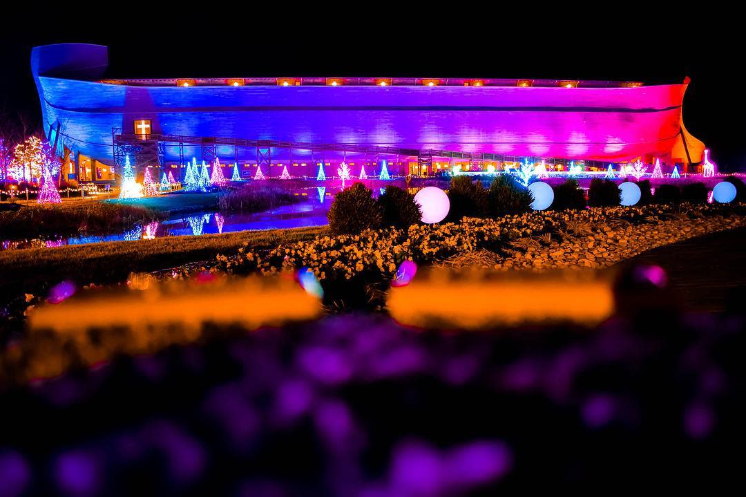 Image is of the Ark at Christmas lit up with holiday lights around the and on the Ark.