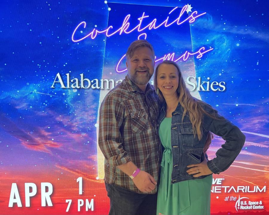 A couple in front of the Cocktails and Cosmos sign at the US Space and Rocket Center