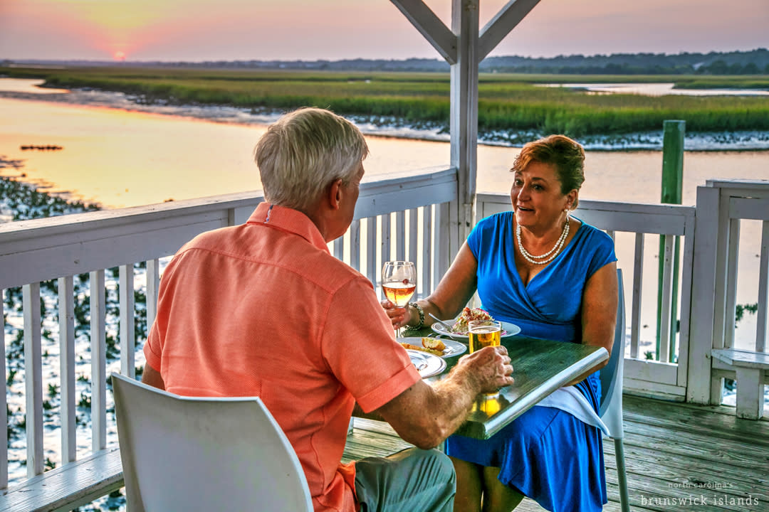 Couple dining on the waterfront at sunset in North Carolina's Brunswick Islands