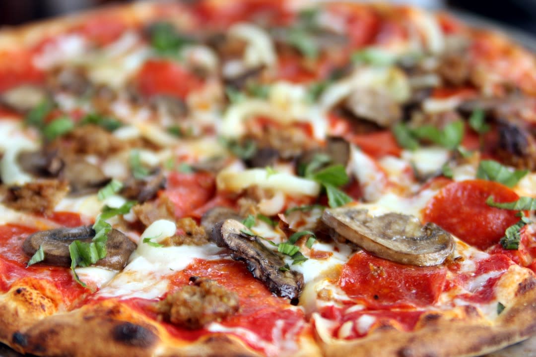 a deluxe pizza featuring pepperoni, mushrooms, onion, sausage and peppers