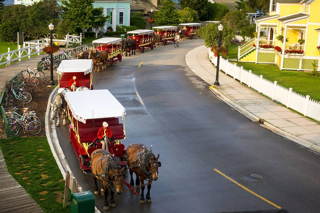 A lineup of horse-drawn carriages stretches around a street corner on Mackinac Island
