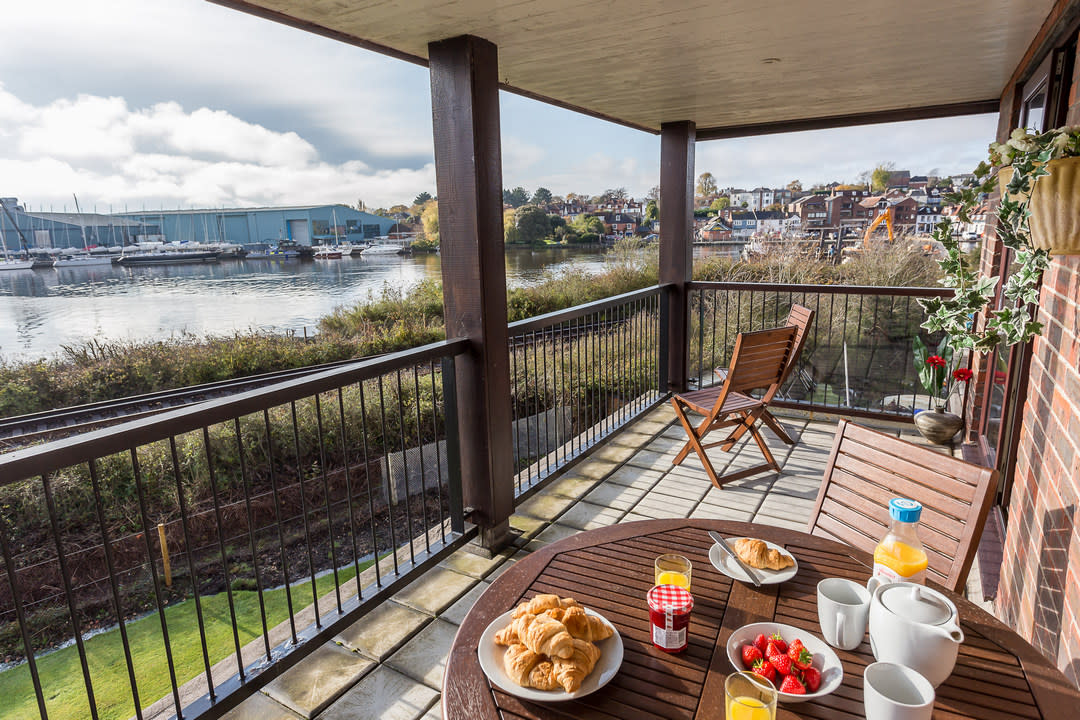 breakfast set out on a table on an outdoor patio overlooking the water