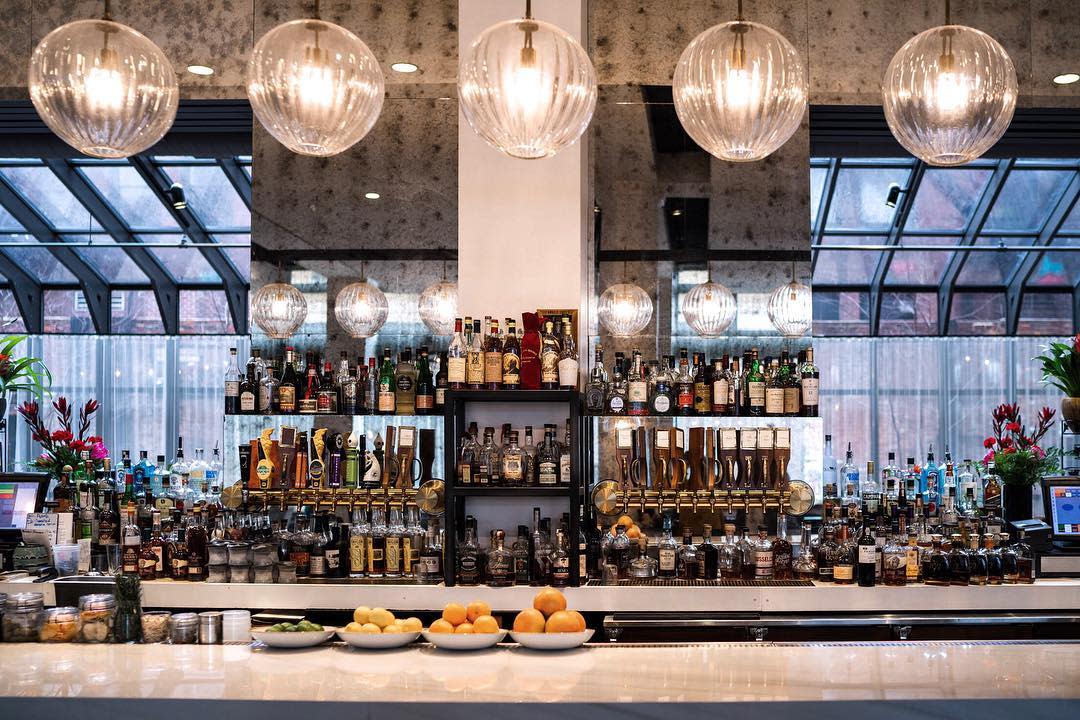 the bar at coppins at hotel covington with plates of oranges, lemons, limes and shelves of alcohol with globe lights above