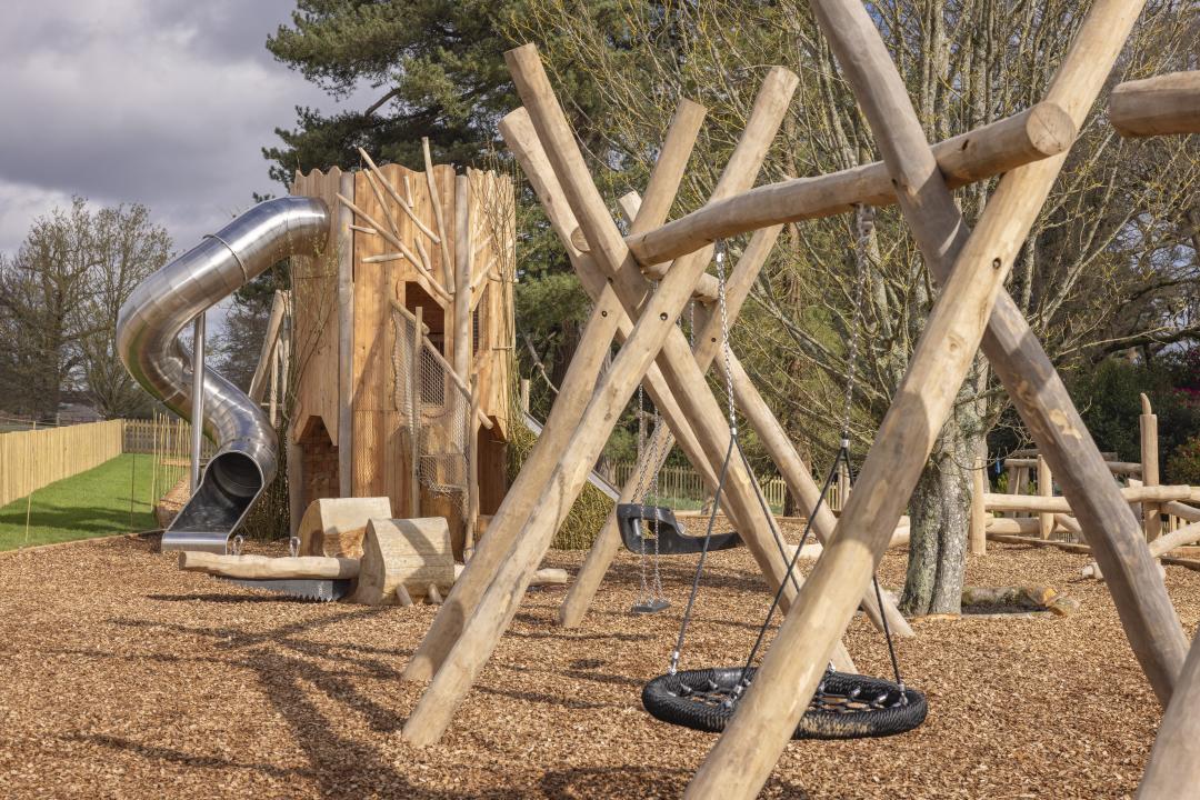 outdoor play area at Leonardslee Lake & Garden showing wooden climbing structures and a spiral slide