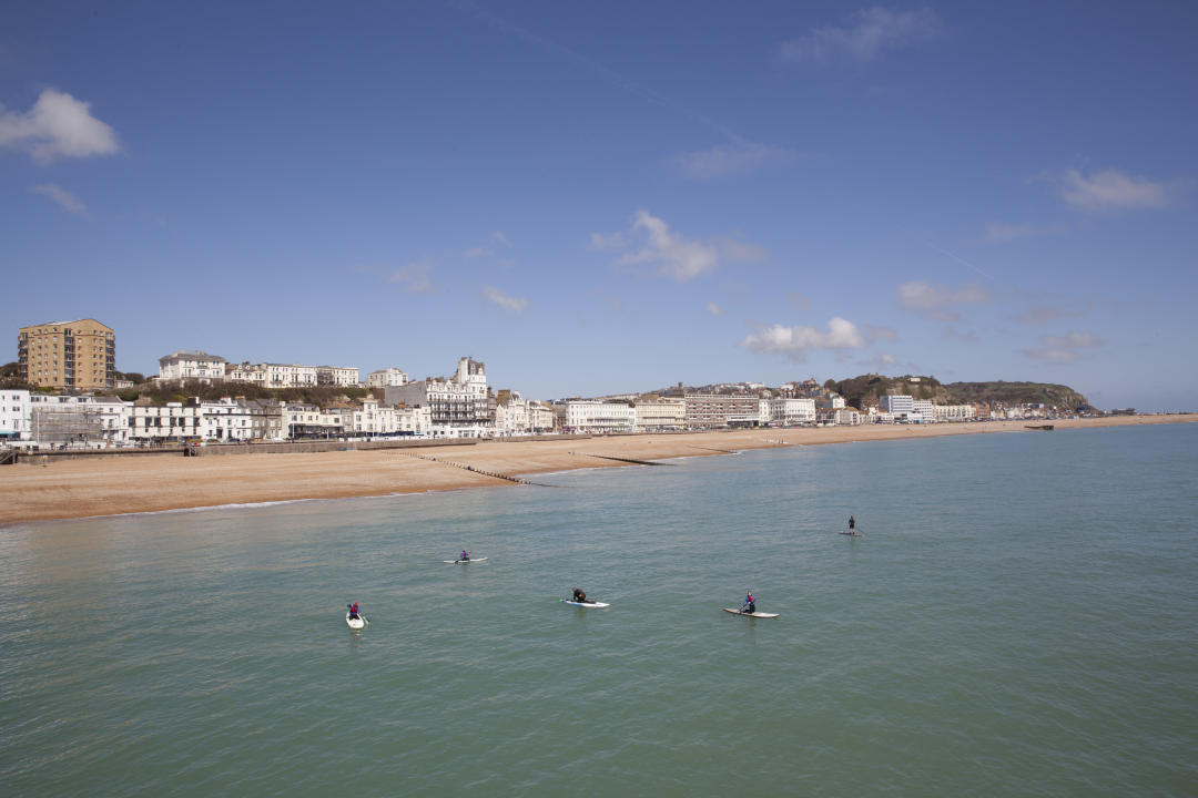 Group of paddleboarders on the sea with Hastings and beach in the backgroud
