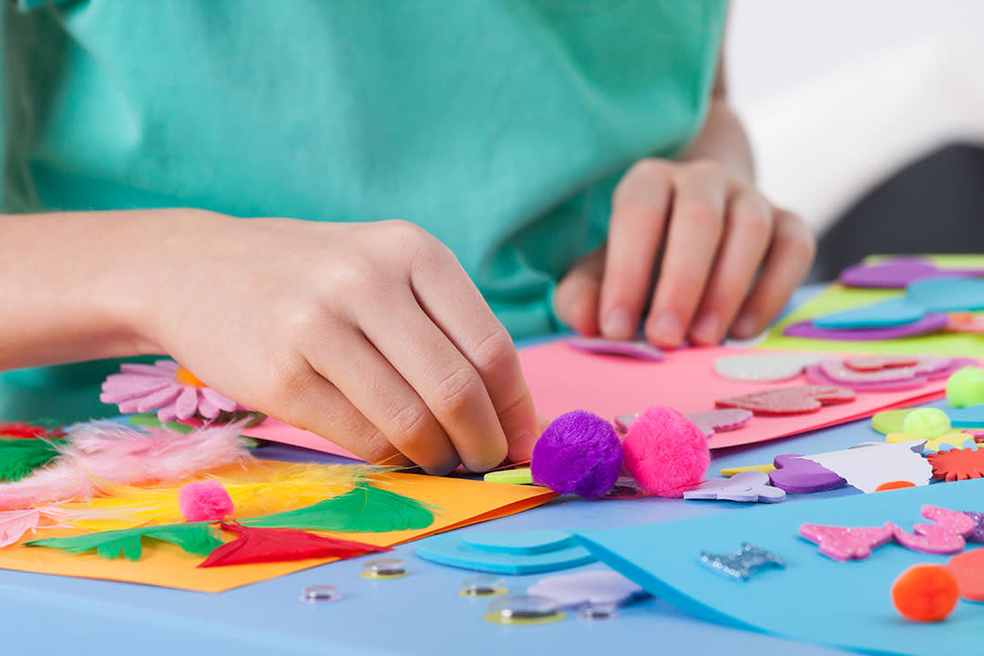 A child's hands on a crafting table.