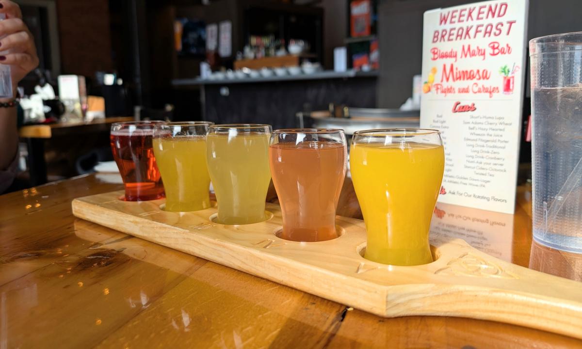 A mimosa flight with five different mimosas on a wooden board.