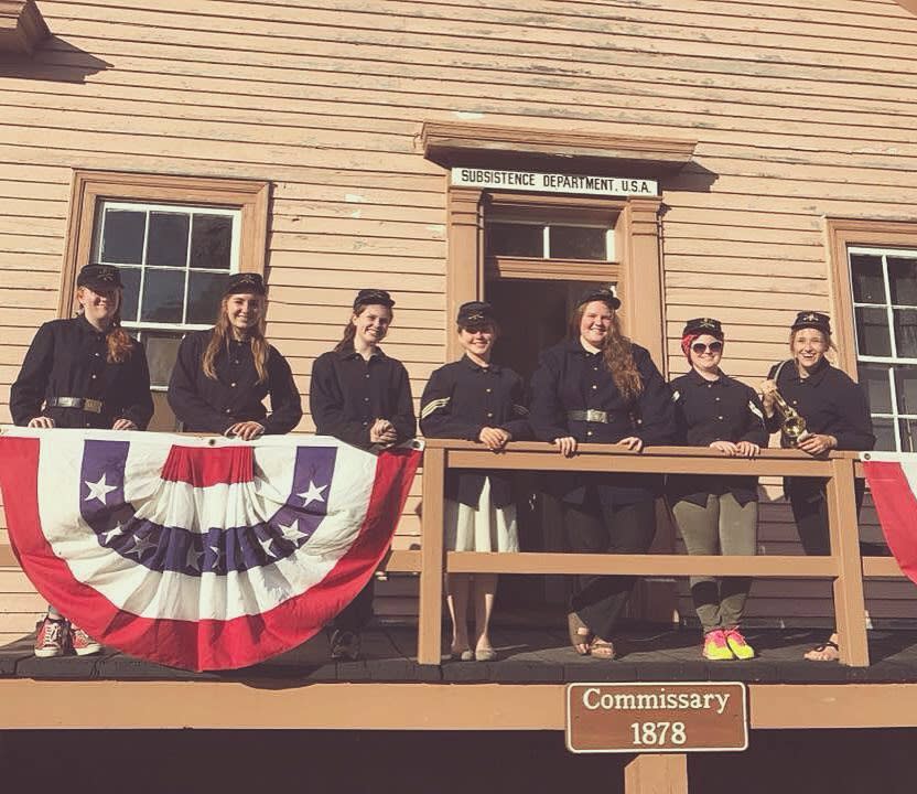 A group of historical interpreters stand in front of a building at Mackinac Island's Fort Mackinac