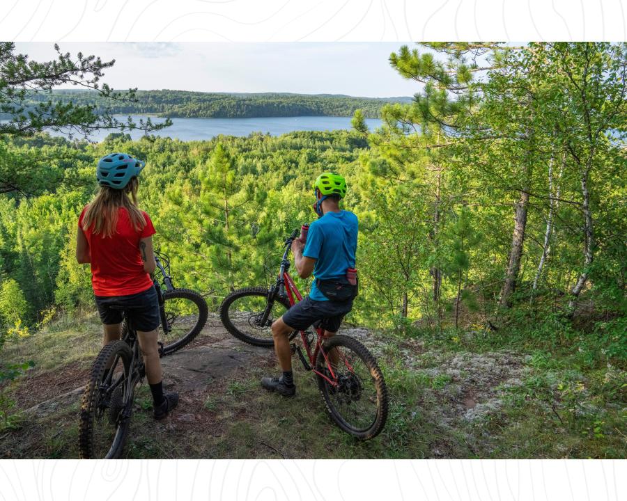A couple overlooking the scenic lake view from a forested RAMBA trail in Ishpeming, MI