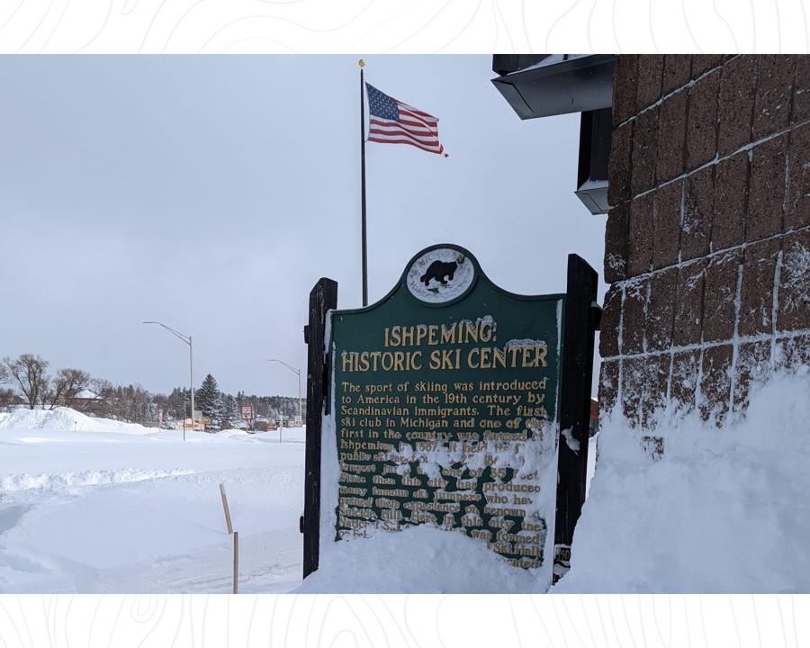 "Ishpeming Historic Ski Center" sign covered by feet of snow outside of the US Ski & Snowboard Hall of Fame in Ishpeming, MI