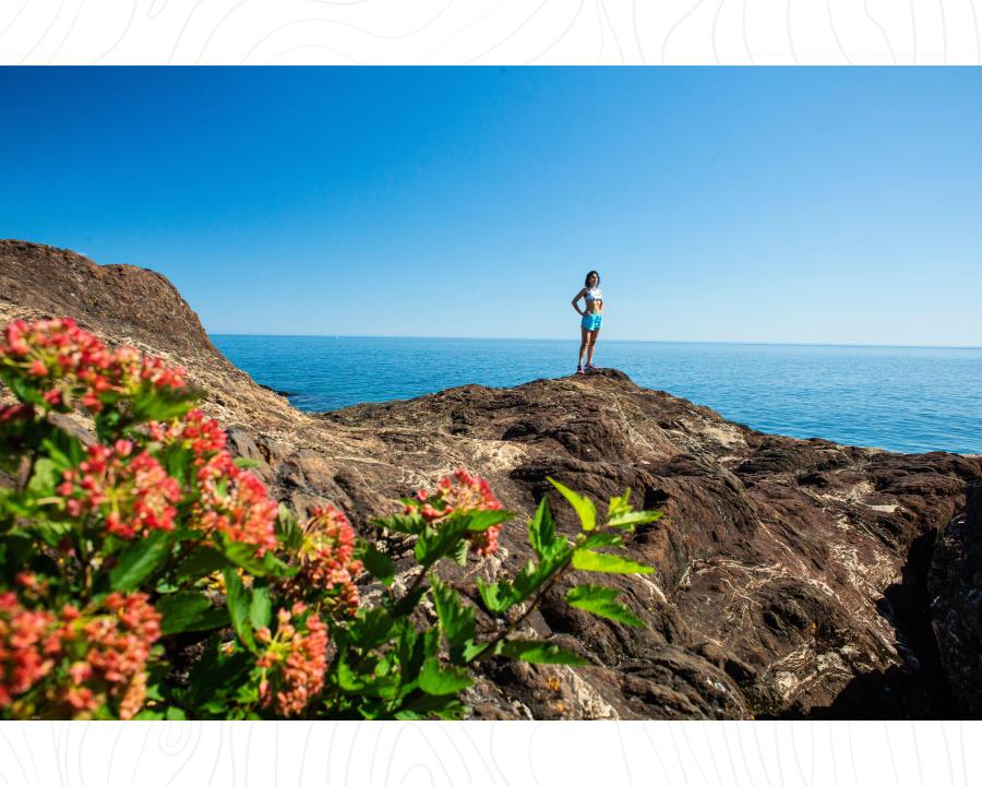 A woman standing on the ancient black rocks along Lake Superior in Marquette, MI