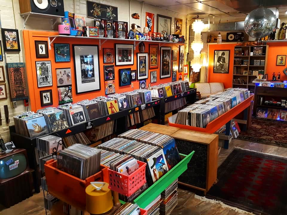 shelves of records, speakers above, disco ball and light hanging in back corner