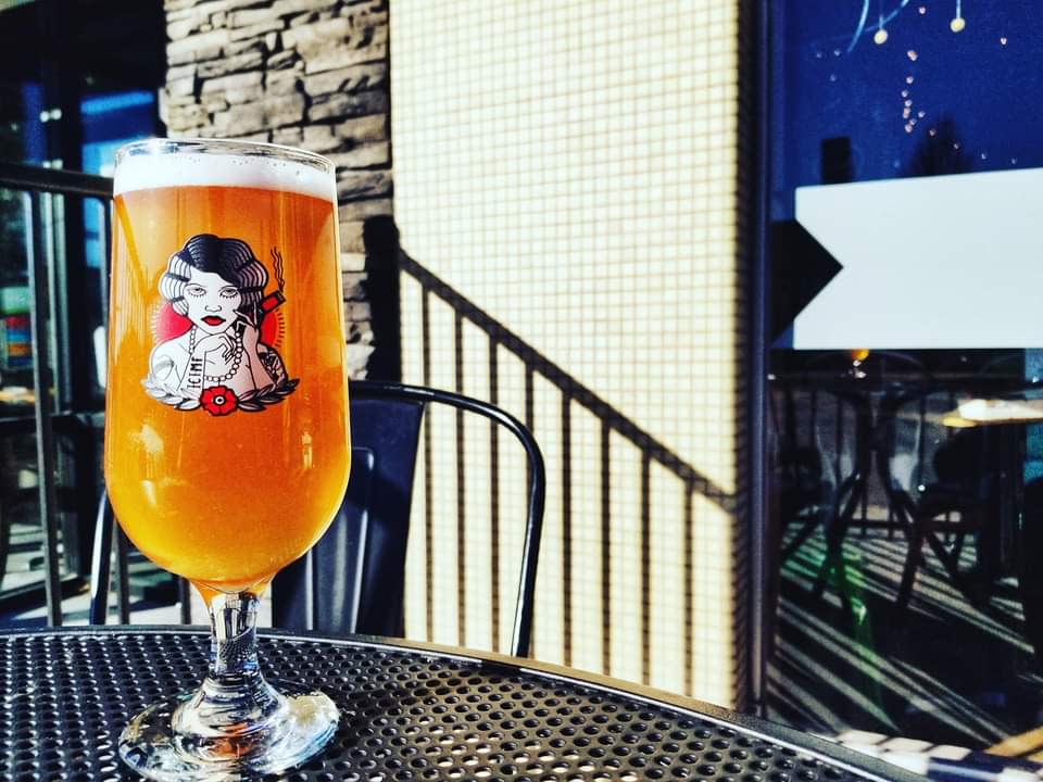A full beer is set on an iron table on the outdoor patio of Hopping Gnome Brewing Company