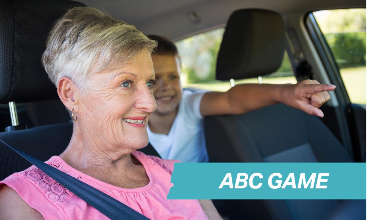 Image of a woman in pink looking forward in a car with a child in the backseat pointing forward. Text in the bottom right corner that says ABC Game.