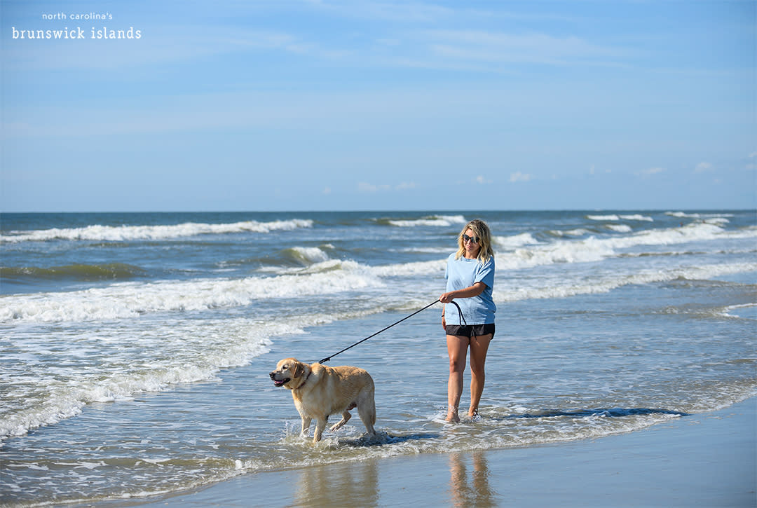 woman walking dog in the surf