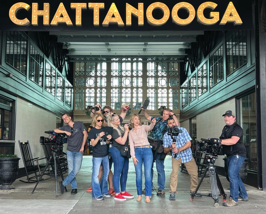 Samantha Brown and TV crew stand under big CHATTANOOGA sign at the Chattanooga Choo Choo