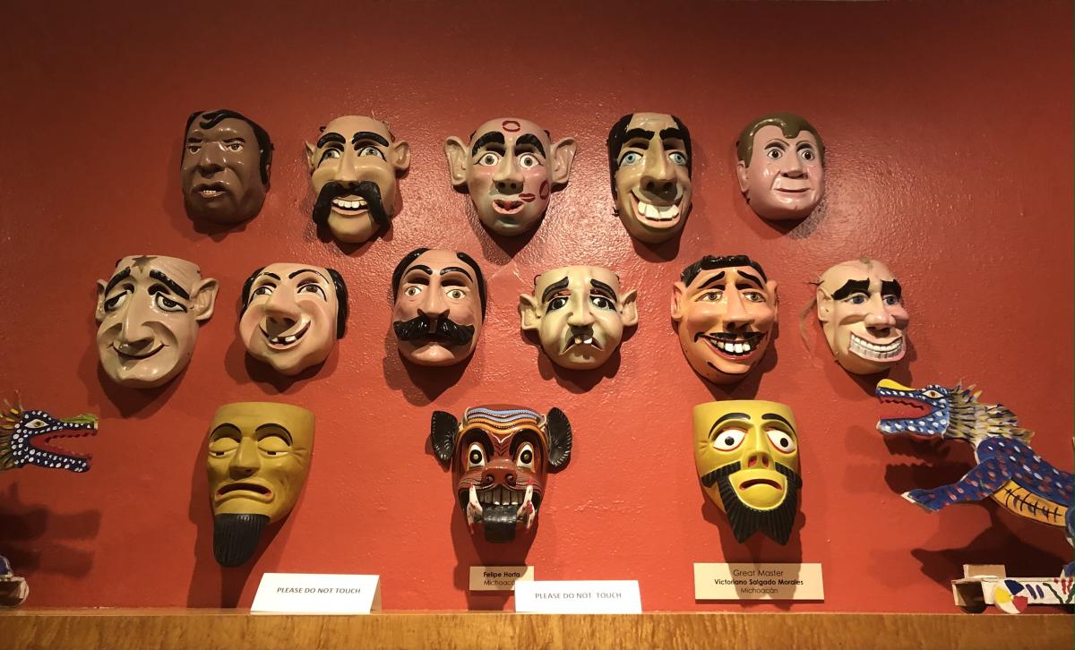 A collection of character masks are displayed on a wall at the Coachella Valley History Museum.
