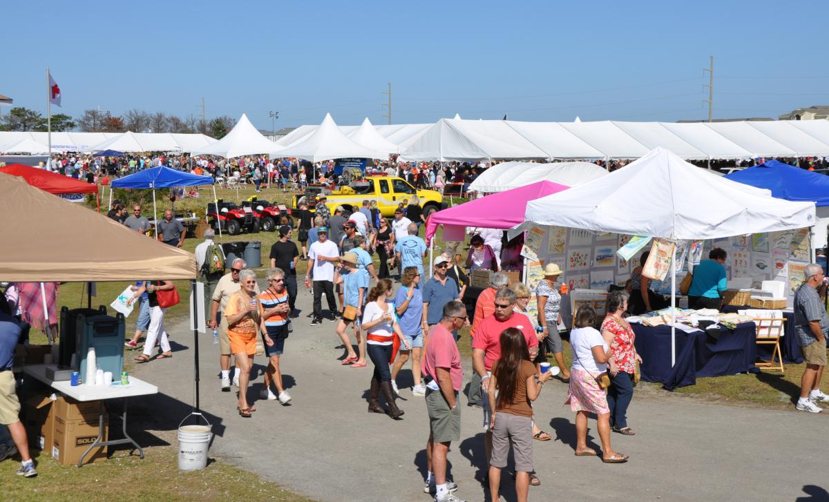 People walking around The Outer Banks Seafood Festival on a bright, sunny day.