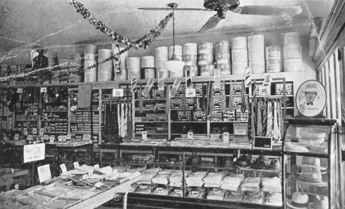 Christmas garland over tie racks, glass display cases and stacked hat boxes inside The Paris clothing store in Sylva, NC, in the 1920s