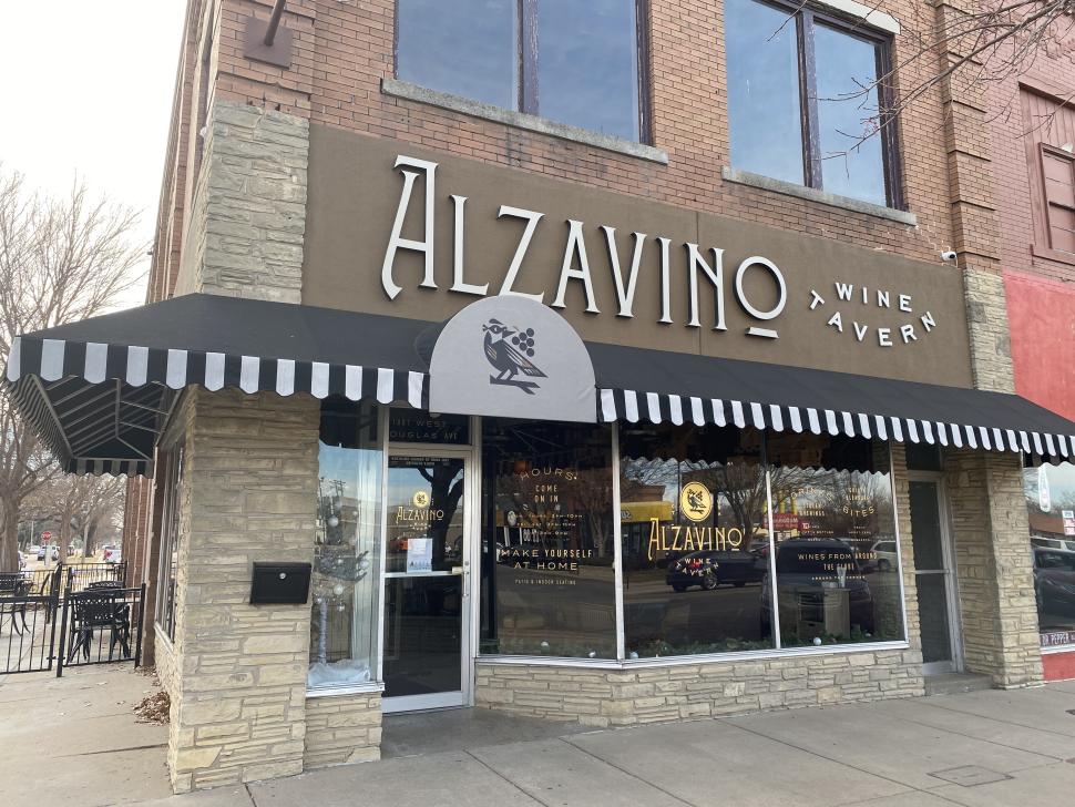 Exterior of a downtown stone building with a black awning and a sign reading "Alzavino Wine Tavern"