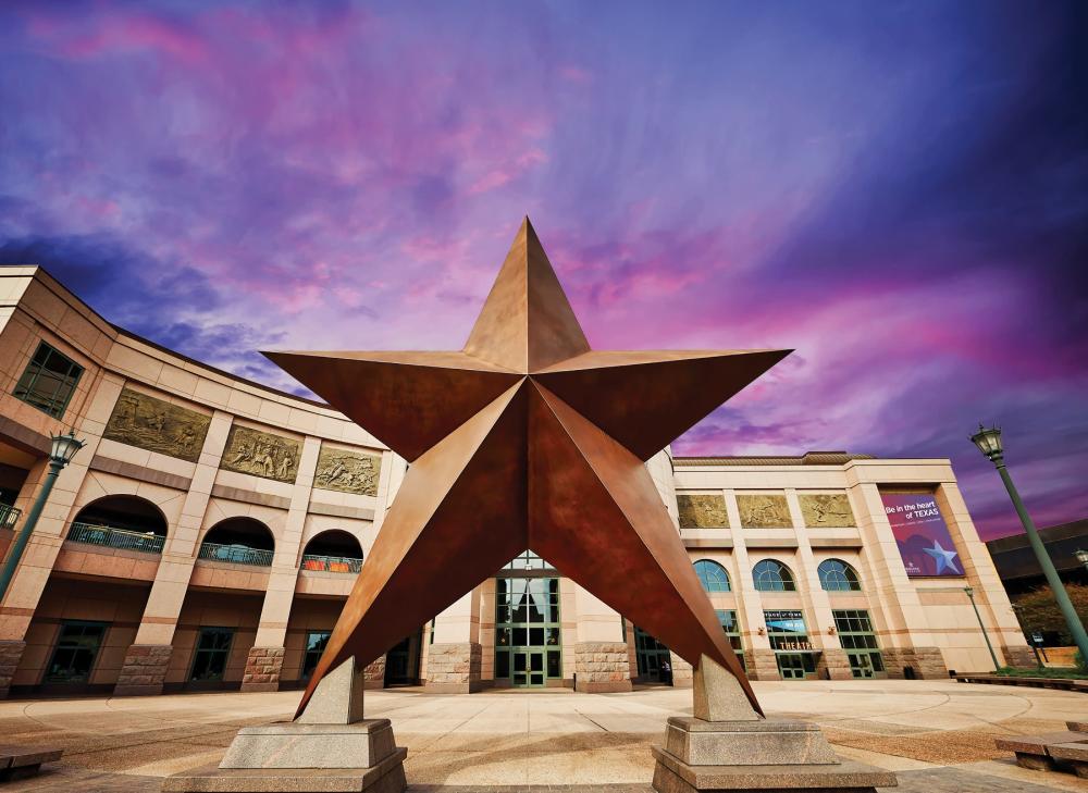 Looking up at the giant iron star in front of the Bullock Museum, with a purple hued sky in the background.