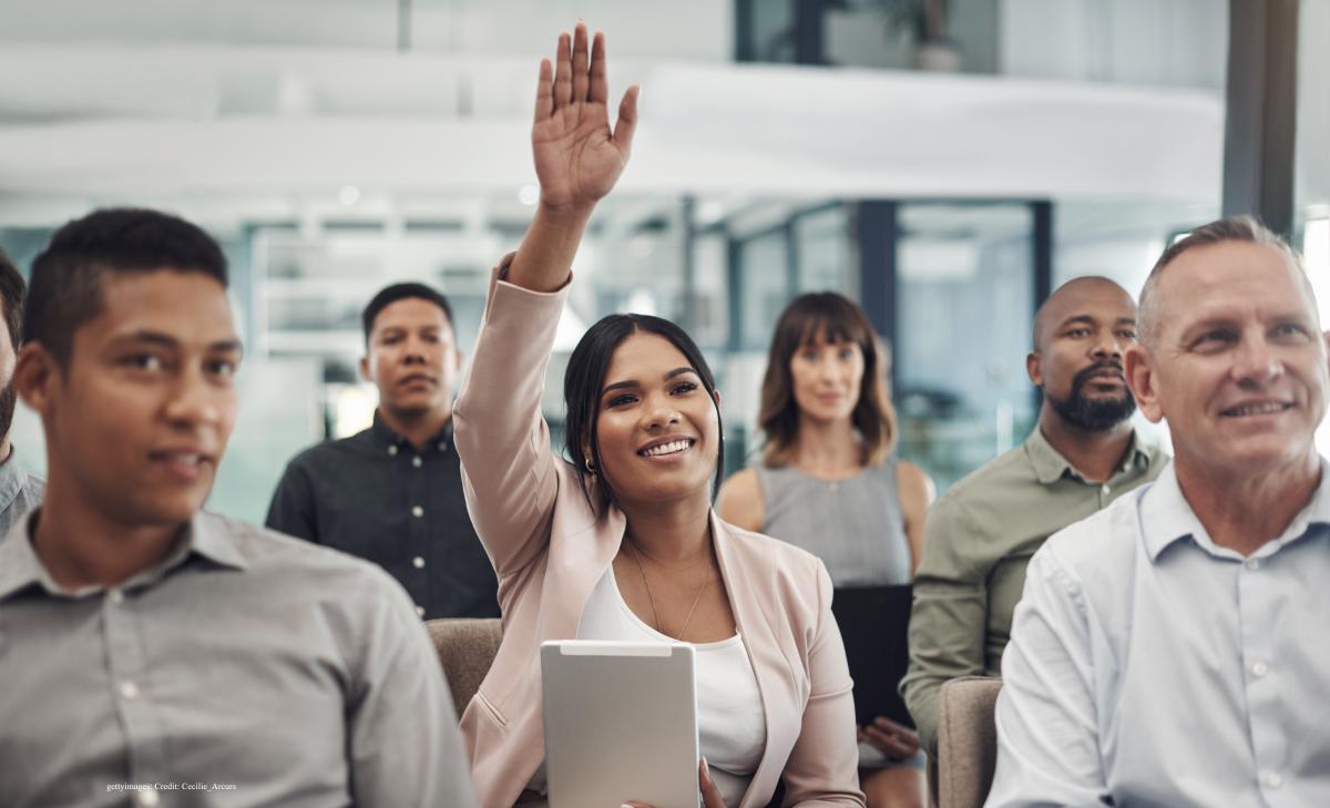 Woman raises hand in a meeting