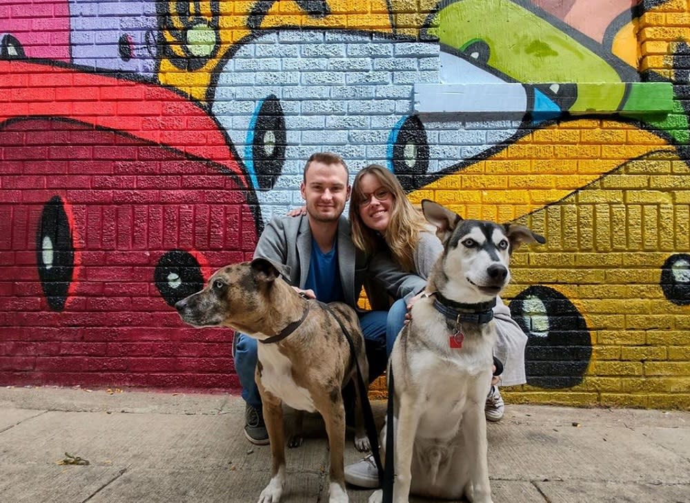 Couple with dogs pose in front of mural