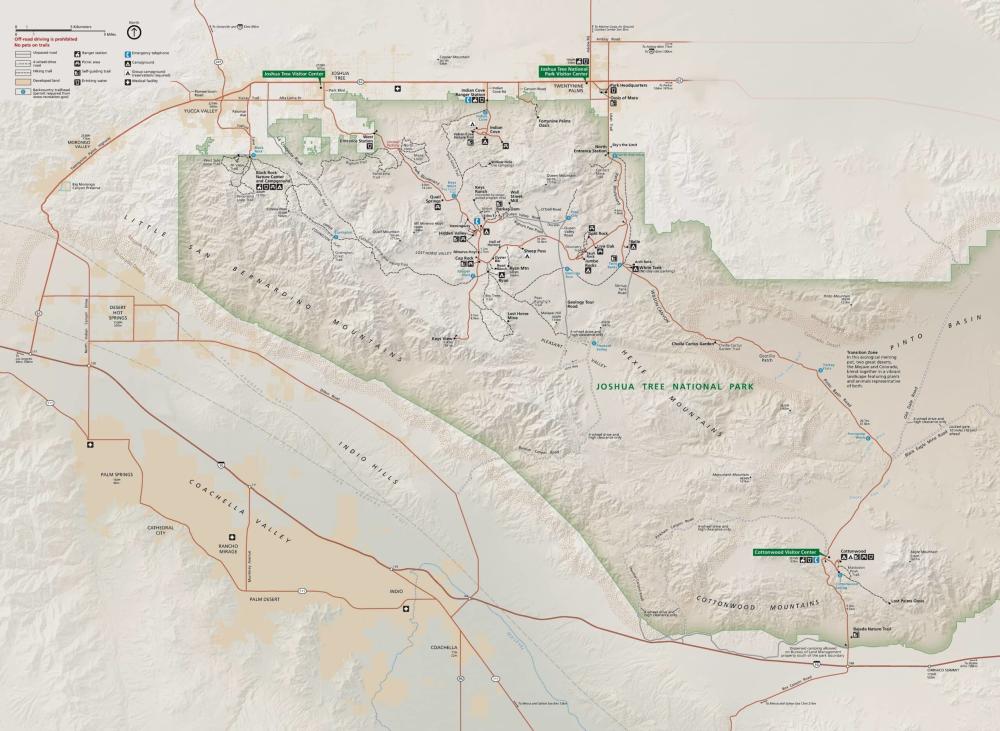 Alt text: A detailed map of Joshua Tree National Park, depicting roads, trails, campgrounds, visitor centers, and points of interest with a legend and topographical features. Surrounding areas like Coachella Valley, Palm Springs, and towns of Twentynine Palms and Joshua Tree are also shown.