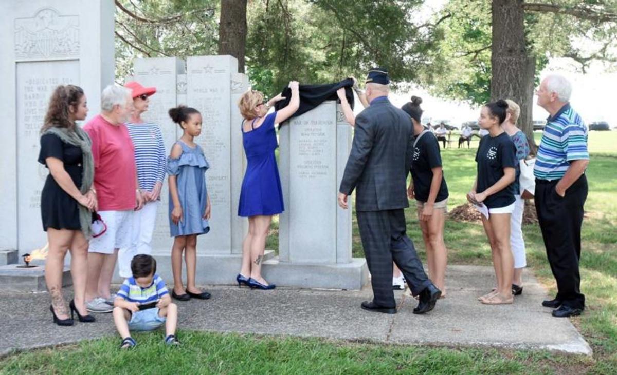 people unveiling names on the american legion memorial