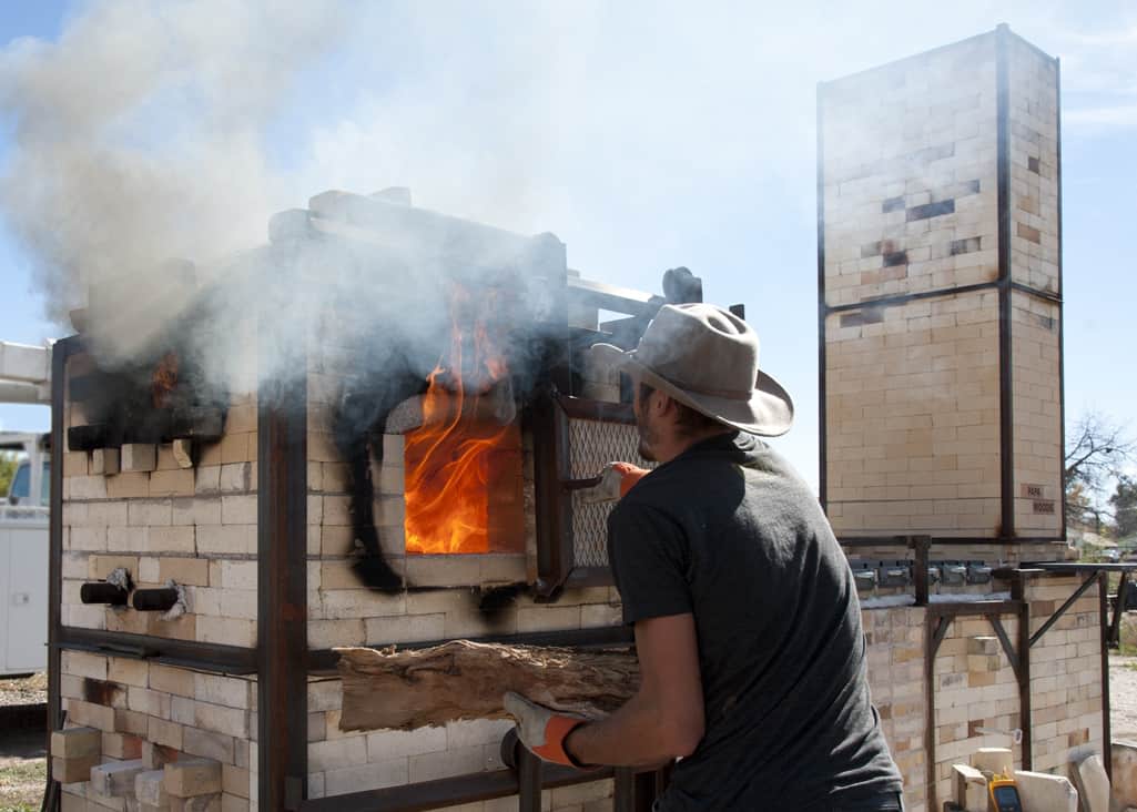 Matt, a sculptor at the Clay Center adds pottery to the fire box